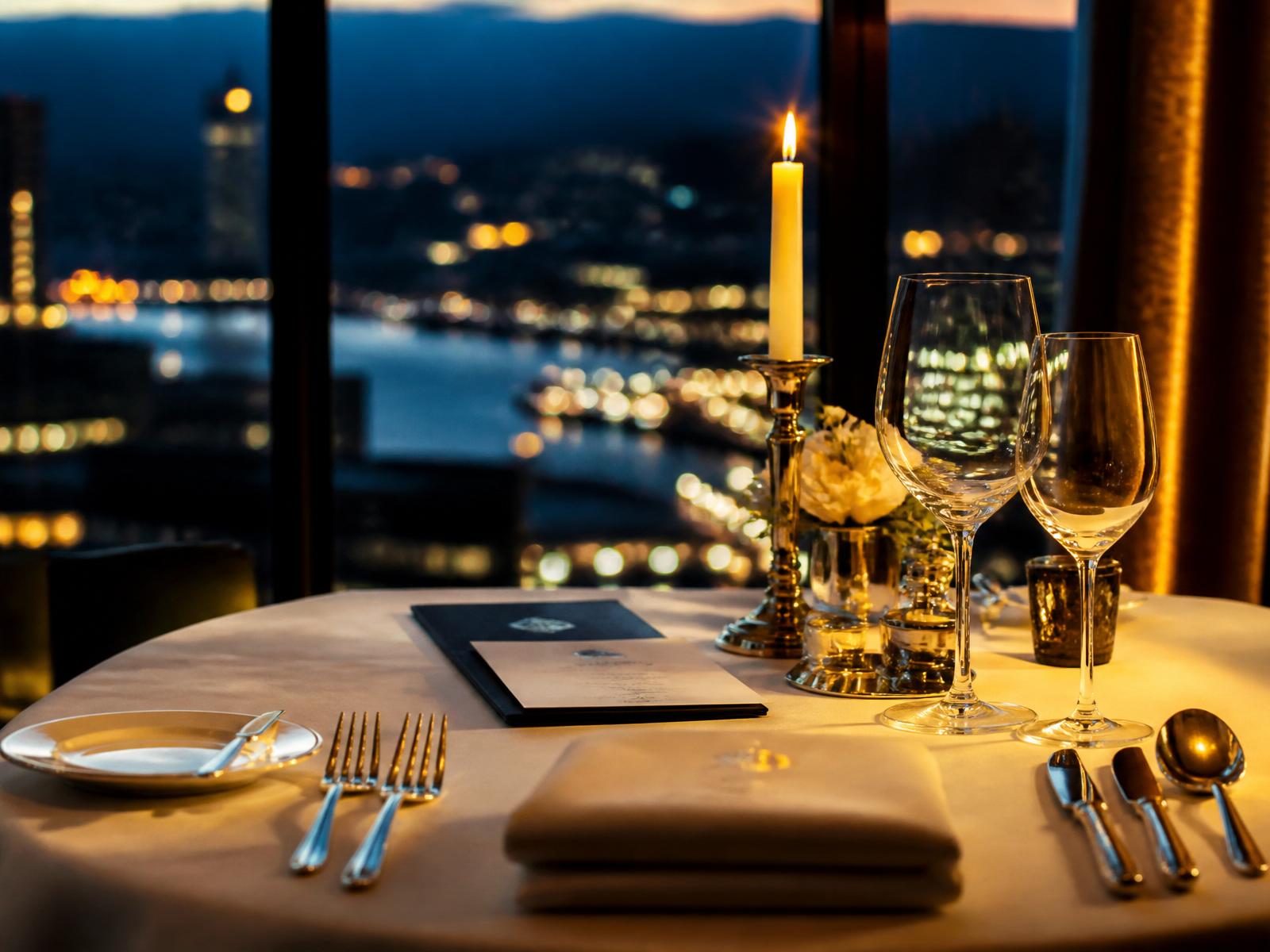 Elegantly set fine-dining table at dusk with crystal glassware and a single candle